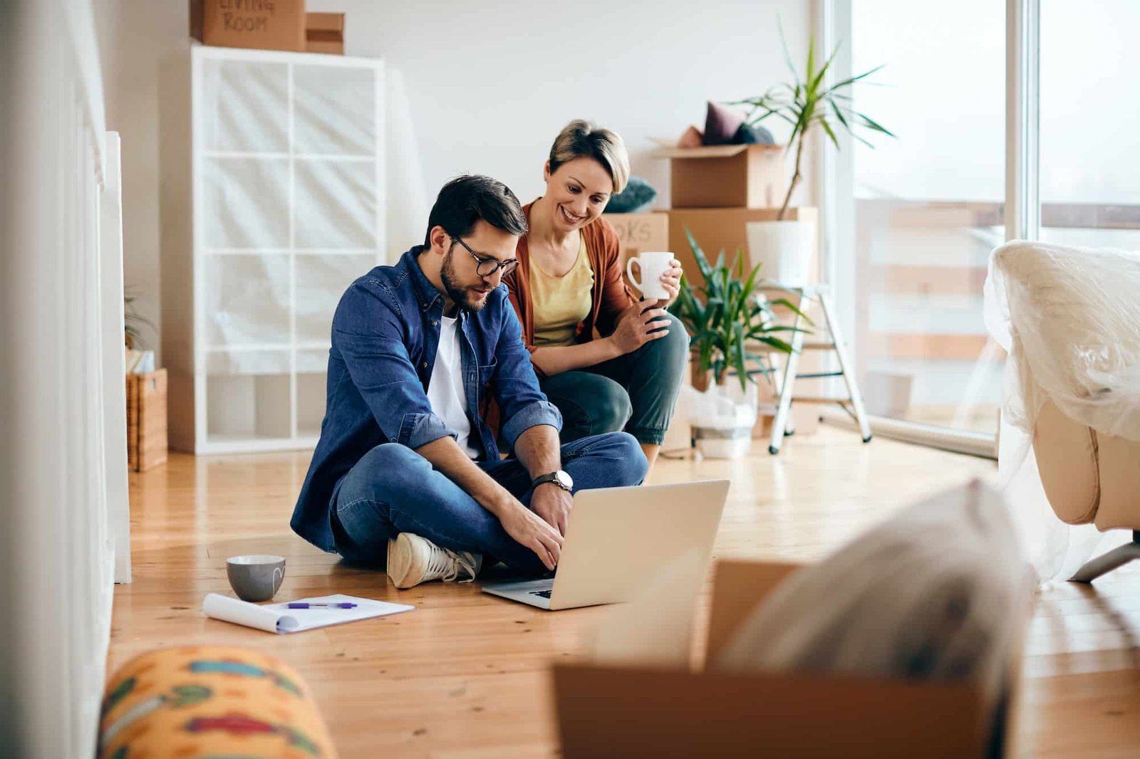Happy couple using laptop while moving into a new apartment. client site internet artisan