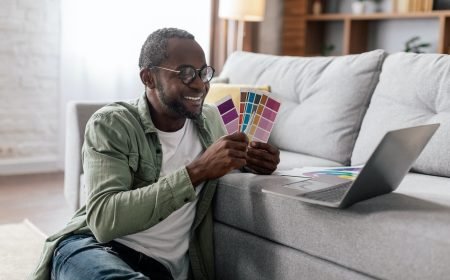 Cheerful adult black businessman designer in glasses and casual show color palettes in laptop in Cheerful adult black businessman designer in glasses and casual show color palettes in laptop in