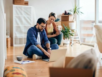 Happy couple using laptop while moving into a new apartment. client site internet artisan